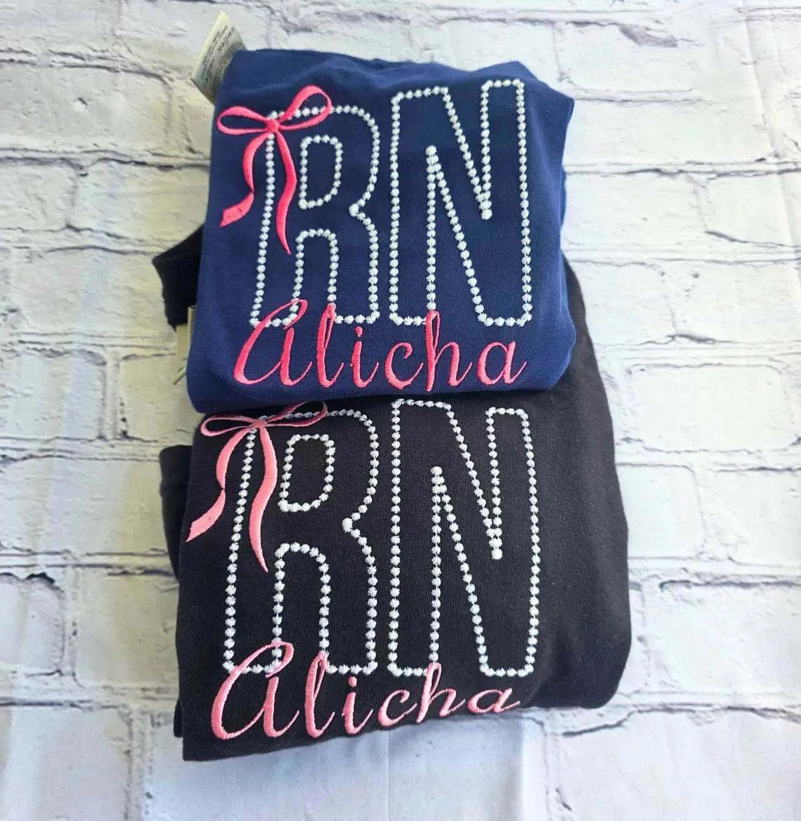 Two shirts with 'RN Alisha' text on a textured surface.custom-nurse-shirt