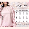 Pink sweatshirt with size chart overlay on a blurred background