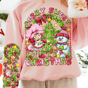 Pink sweatshirt with Christmas-themed design featuring a snowman, girl, and tree.