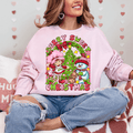 Person wearing a pink sweatshirt with a Christmas-themed design, sitting on a couch.