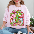Person wearing a pink sweatshirt with Christmas-themed design featuring a snowman, tree, and cartoon characters.