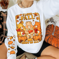 Person wearing a white sweatshirt with 'I Love Fall Most of All' graphic featuring bears and pumpkins. cozy-fall-bear-sweatshirt