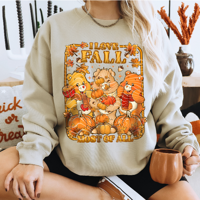 Person wearing a beige sweatshirt with 'I love Fall most of all' and bear . cozy-fall-bear-sweatshirtgraphics.