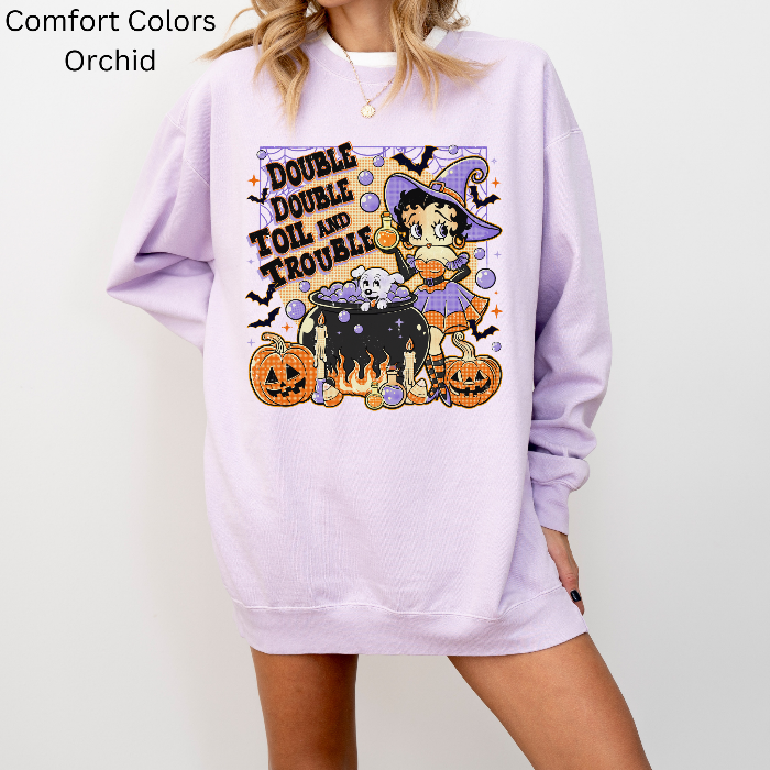 Person wearing a lavender sweatshirt with a Halloween-themed design featuring a cartoon character and text.