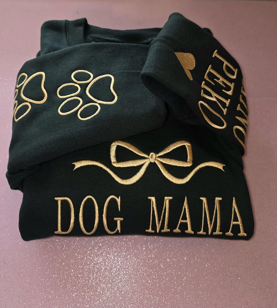 Black sweatshirt with gold text and designs on a pink surface.custom-couple-shirt