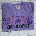 Folded purple t-shirt with radiology-themed graphics and the word 'Radiologist' on a textured gray background.radiologist-t-shirt