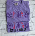 Folded purple t-shirt with radiology-themed graphics on a textured gray background.radiologist-t-shirt