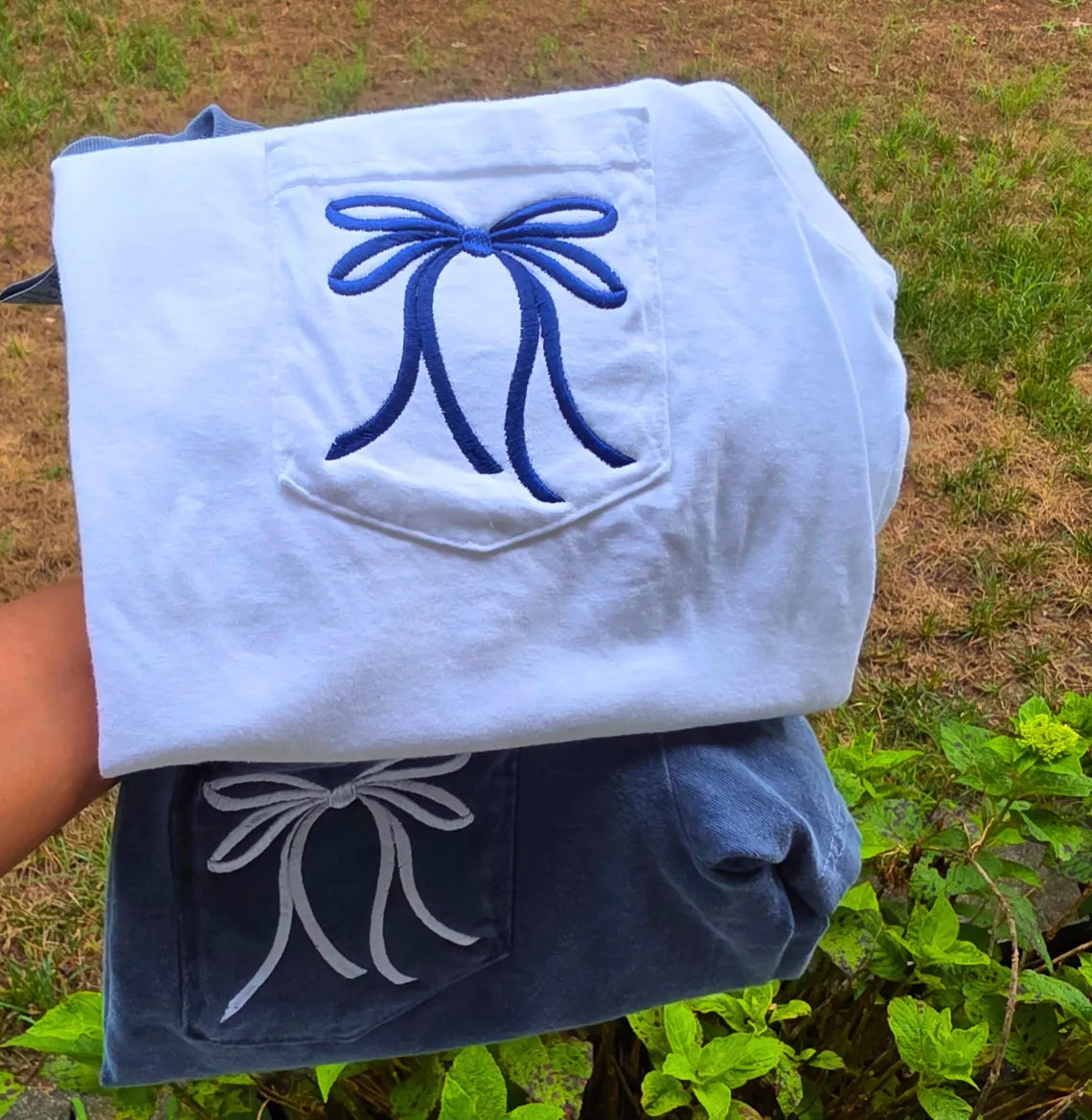White and blue fabric with embroidered designs held by a person outdoors.