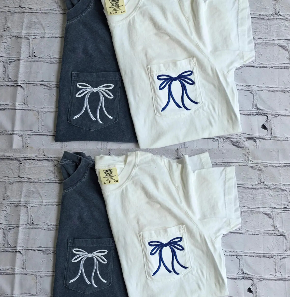 Two navy and two white t-shirts with bow designs on a textured gray surface