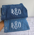 Folded denim jacket with 'AEO' monogram on a light gray surface.custom-bridesmaid-jackets