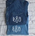 Folded denim vest with 'A&EO' monogram on a textured white .custom-bridesmaid-jacketsbackground