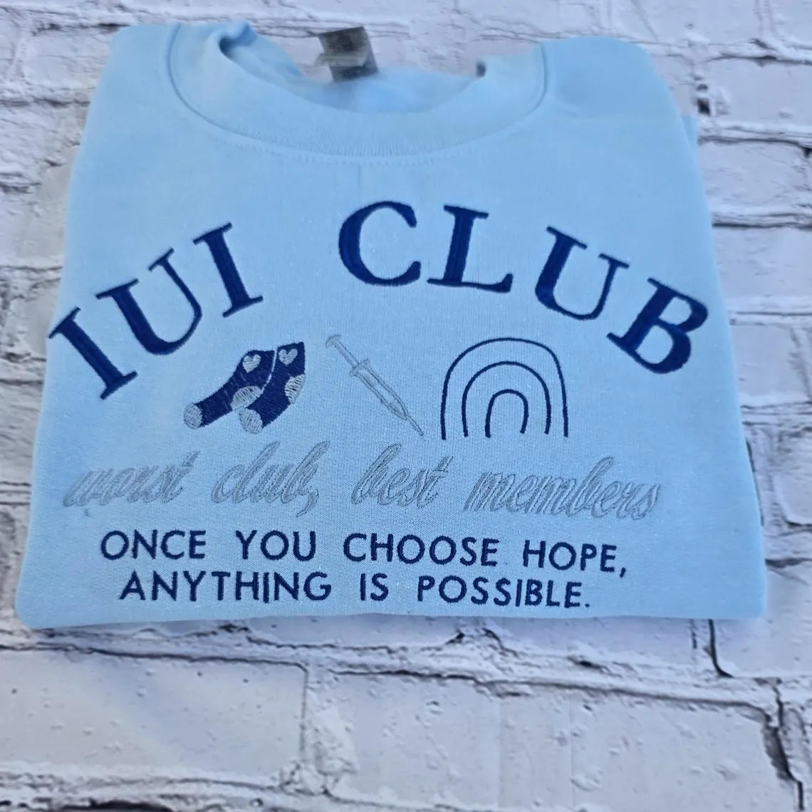 Light blue sweatshirt with 'IUI Club' text and graphics on a textured white background. ivf-sweatshirt