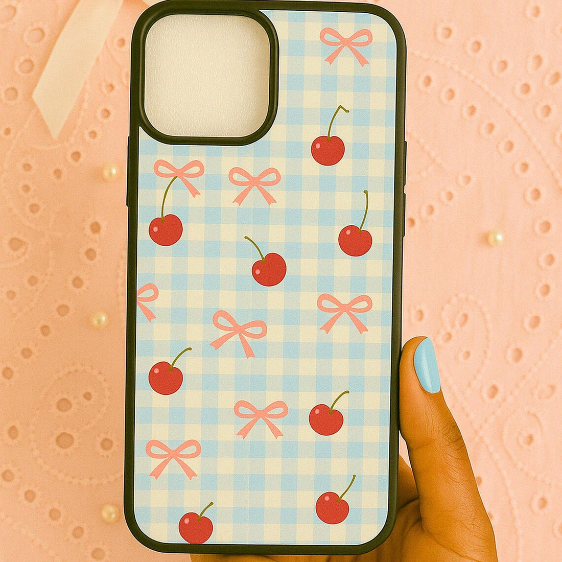 Phone case with cherry and bow pattern on a wooden surface.coquette-phone-case