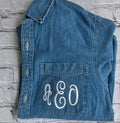 Blue denim vest with 'R&O' monogram on a textured gray background.custom-bridesmaid-jackets