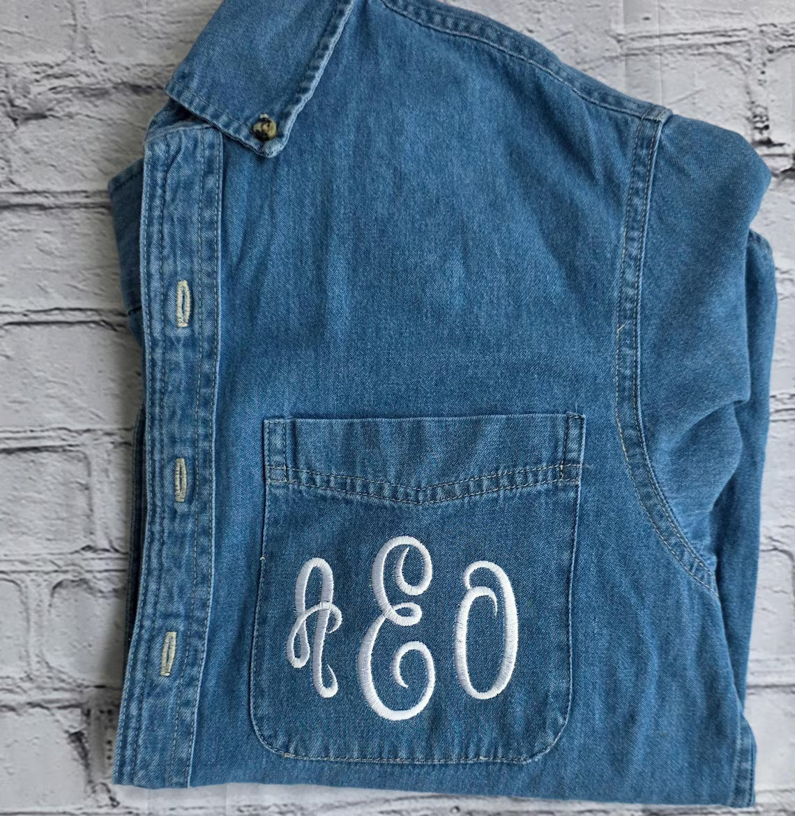 Blue denim vest with 'R&O' monogram on a textured gray background.custom-bridesmaid-jackets