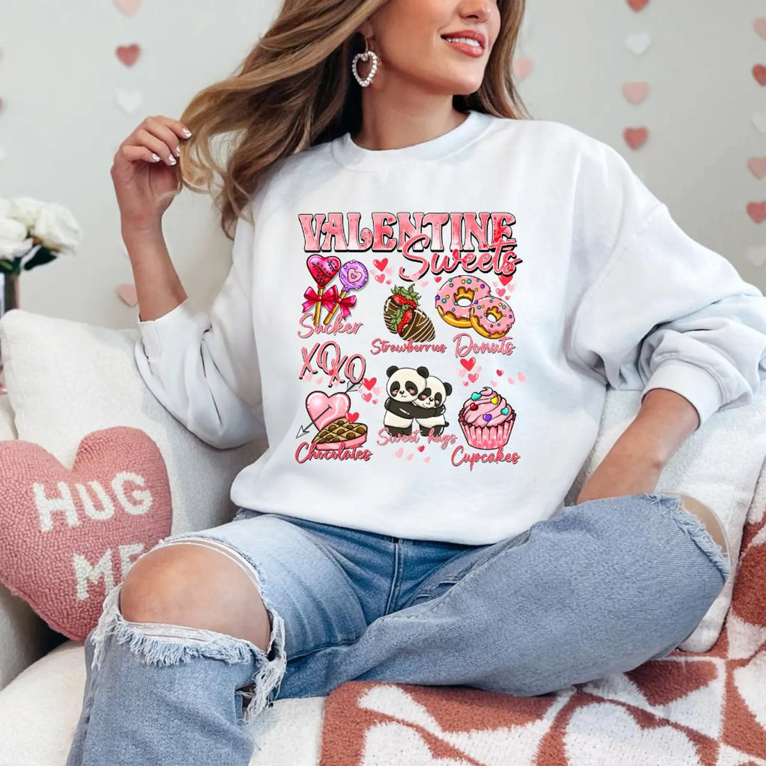 A woman sitting and smiling, wearing a black sweatshirt with a Valentine's Day-themed graphic, surrounded by red heart-shaped balloons.valentines-sweatshirt-for-women