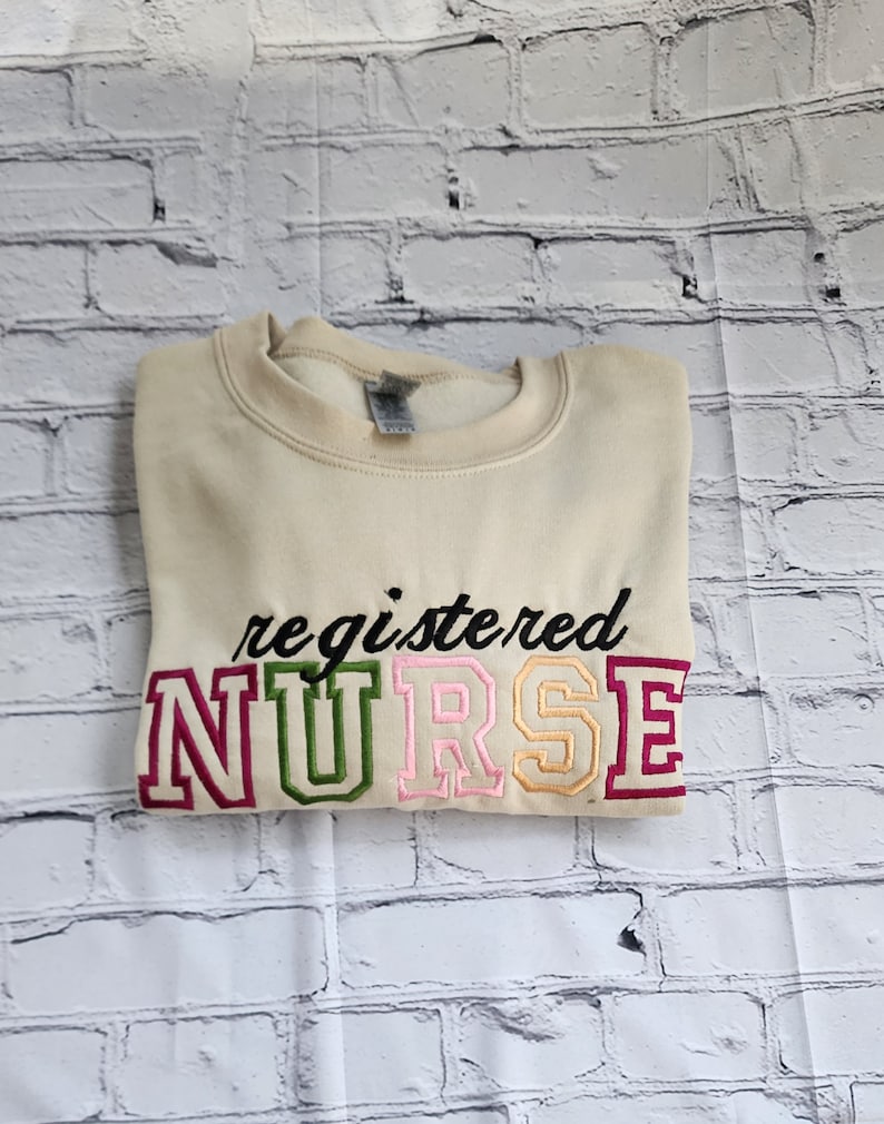 A collection of embroidered crewneck sweatshirts with the word 'NURSE' and 'registered NURSE' embroidered in various colors.