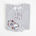  a light sweatshirt with a spooky nurse-themed design, including illustrations of ghosts and medical equipment, paired with black pants.