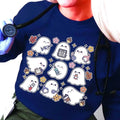 A woman wearing a blue sweatshirt with a spooky nurse-themed design, including illustrations of ghosts and medical equipment, paired with black pants.