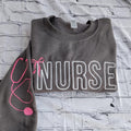 A collection of custom embroidered grey nurse shirts with various titles and names embroidered on the left side of the chest.