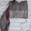 A collection of custom embroidered grey nurse shirts with various titles and names embroidered on the left side of the chest.